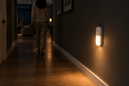 Motion sensor LED night light glowing in a modern hallway at night as someone walks past